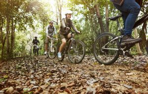 group of friends ride mountain bike in the forest together scaled e1646988867168